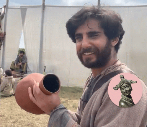 Man With Beard Holding Vase With Statue Of Jester GIF