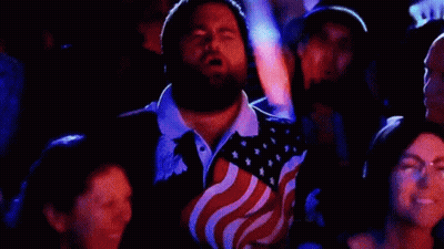 Man With Beard In American Flag Shirt Sitting In Crowd GIF