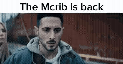 Man With Beard In Front Of Red Building Saying The McRib Is Back GIF