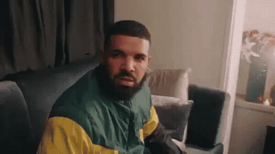 Man With Beard In Green And Yellow Jacket Sitting On Couch GIF