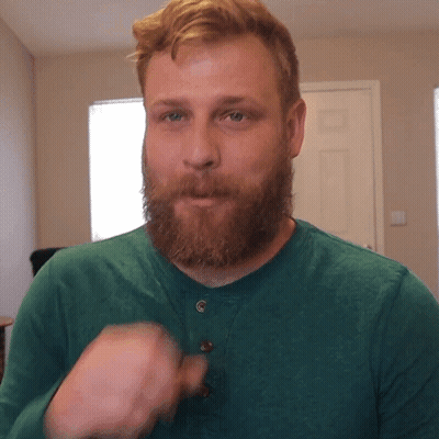 Man With Beard In Green Shirt Looks At Camera GIF