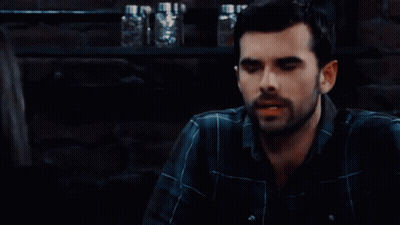 Man With Beard In Plaid Shirt Sitting In Dark Room GIF