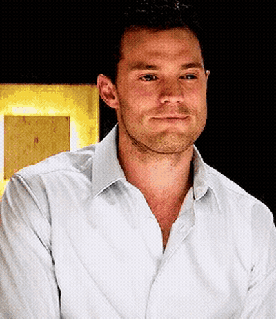 Man With Beard In White Shirt Looks At Camera GIF