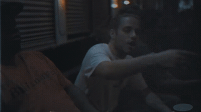 Man With Beard In White Shirt Sitting In Dark Room GIF