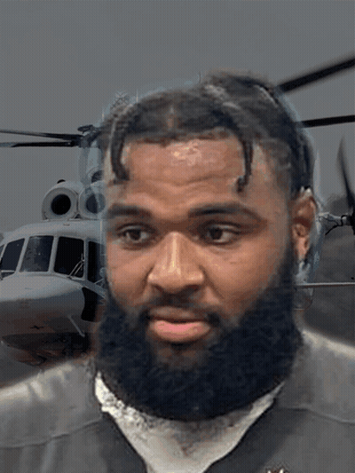 Man With Beard Looking At Camera With Helicopter Background GIF