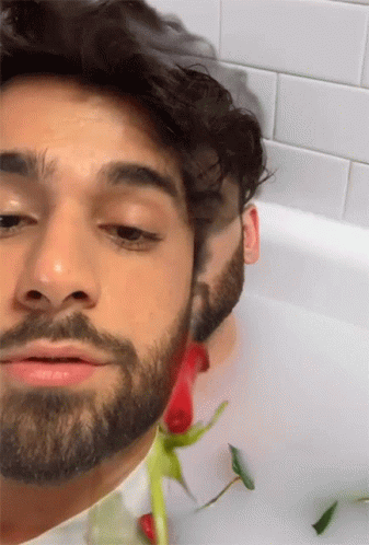 Man With Beard Lying In Bathtub With Rose GIF