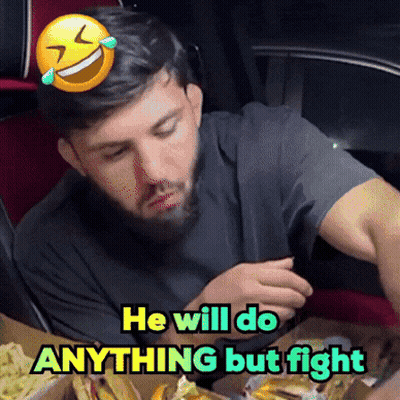 Man With Beard Sitting At Table With Smiley Face Saying He Will Do Anything But Fight GIF