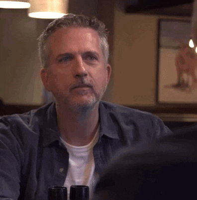 Man With Beard Sitting At Table With Wine Bottles GIF