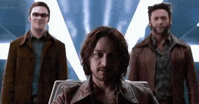 Man With Beard Sitting In Chair With Two Men Standing Behind GIF