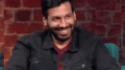 Man With Beard Sitting In Front Of Brick Wall Hand On Chest GIF