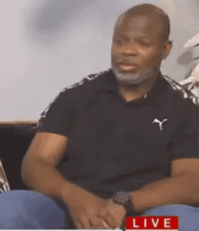 Man With Beard Sitting On Couch In Black Polo Shirt GIF