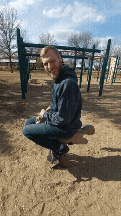Man With Beard Sitting On Seesaw At Playground GIF