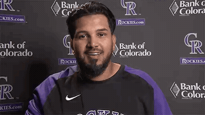 Man With Beard Smiling In Front Of Bank Of Colorado Logos GIF