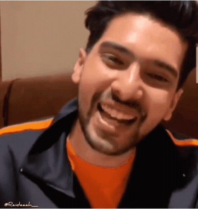 Man With Beard Smiling In Orange Shirt And Black Jacket GIF