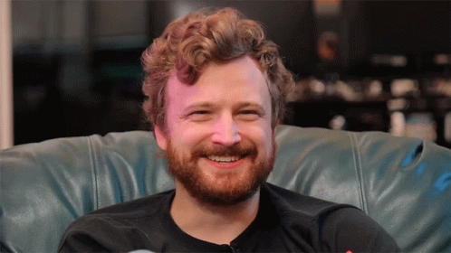 Man With Beard Smiling Sitting On Blue Leather Couch GIF