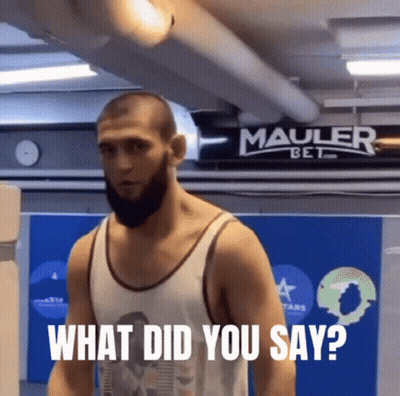 Man With Beard Standing In Front Of Mauler Bet Sign GIF