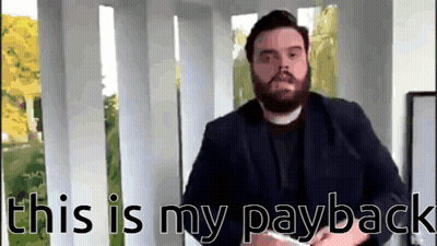 Man With Beard Standing In Front Of This Is My Payback Sign GIF