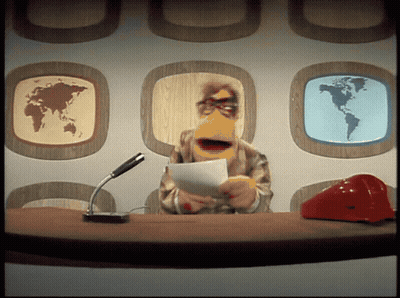 Man With Beard Standing On Stage In Front Of TV Logo GIF