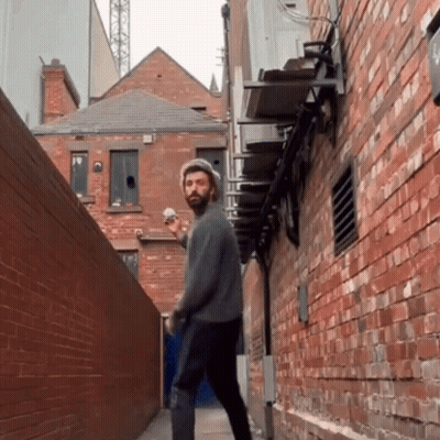 Man With Beard Walking Down Alleyway GIF