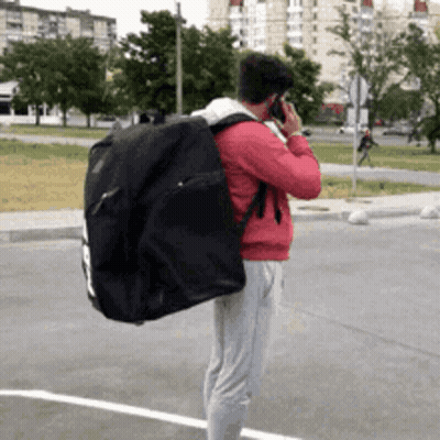 Man With Black Bag Talking On Phone GIF