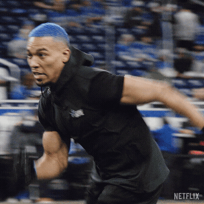 Man With Blue Hair Running In Front Of Netflix Logo GIF