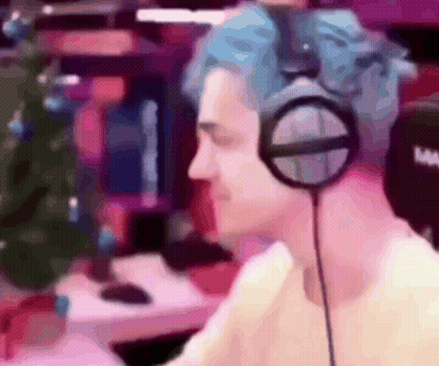 Man With Blue Hair Wearing Headphones In Front Of Christmas Tree GIF