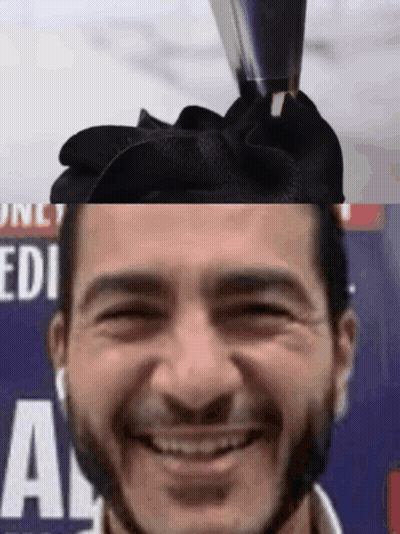 Man With Bow On Head Smiling In Front Of Edi Sign GIF
