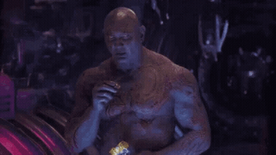 Man With Chest Tattoo Eating Snack In Dark Room GIF
