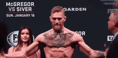 Man With Chest Tattoo In Front Of McGregor Vs Silver Sign GIF