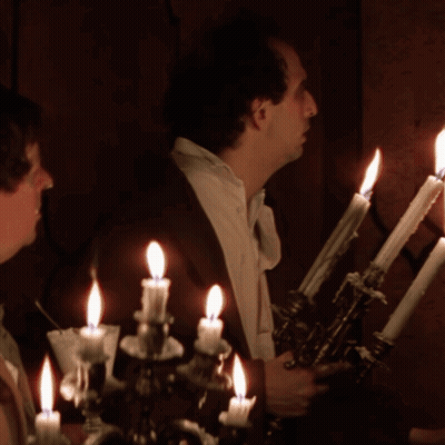 Man With Cigarette In Front Of Candle Holder GIF