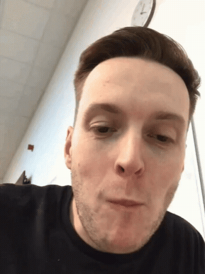 Man With Clock Saying 7:15 Behind Him GIF