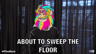 Man With Colorful Monkey On Head About To Sweep Floor GIF