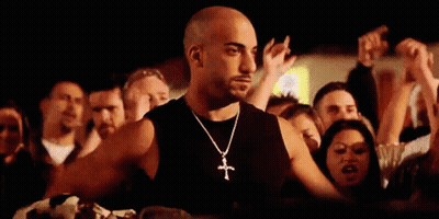 Man With Cross Necklace Standing In Front Of Crowd GIF