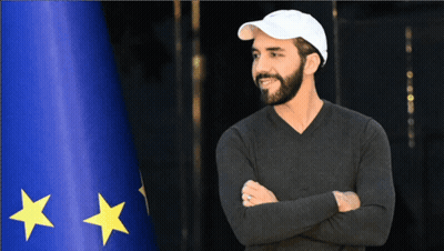 Man With Crossed Arms In Front Of Blue Flag With Yellow Stars GIF