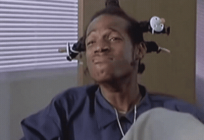 Man With Curlers Sitting By Blinds GIF
