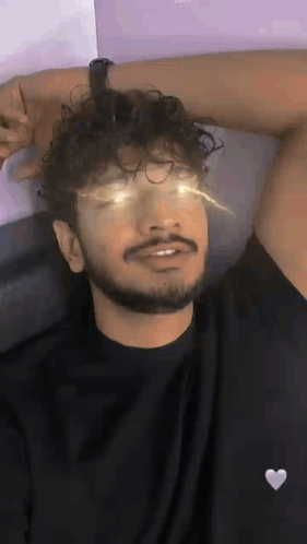 Man With Curly Hair And Beard Laying On Bed Eyes Closed Arm Outstretched GIF