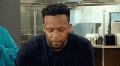 Man With Curly Hair And Beard Sitting In Kitchen Eyes Closed GIF