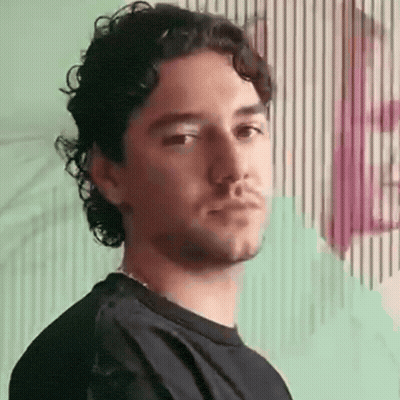 Man With Curly Hair And Beard Standing Before Striped Wall GIF