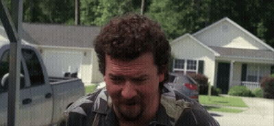 Man With Curly Hair And Beard Standing In Front Of House And Truck GIF