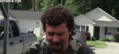 Man With Curly Hair And Beard Standing In Front Of House With Truck GIF