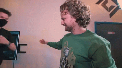 Man With Curly Hair And Beard Wearing Green Shirt And Mask GIF