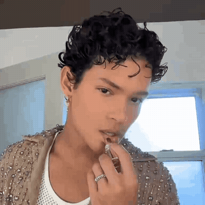 Man With Curly Hair Applying Lipstick GIF