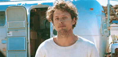 Man With Curly Hair In Front Of Airstream GIF