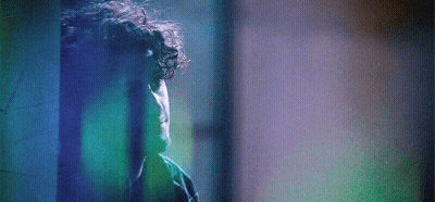 Man With Curly Hair In Front Of Blue Wall GIF