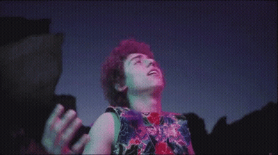 Man With Curly Hair In Front Of Purple Blue Background GIF