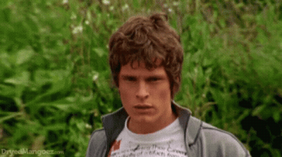 Man With Curly Hair In Gray Jacket And White T-Shirt GIF