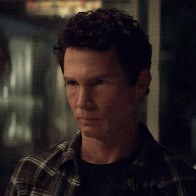 Man With Curly Hair In Plaid Shirt Looking At Camera GIF