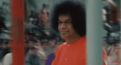 Man With Curly Hair In Red Shirt Standing Before Crowd GIF