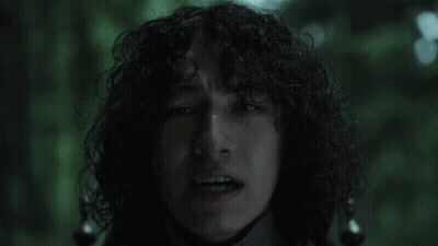 Man With Curly Hair Making Funny Face In Dark GIF