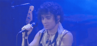 Man With Curly Hair Singing Into Microphone GIF